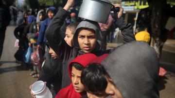 أطفال نازحون ينتظرون الحصول على الطعام في مخيم للاجئين وسط غزة، 2 فبراير 2024 (Getty)