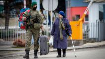 جندي سلوفاكي يساعد مسنّة أوكرانية على الحدود (بيتر لازار/ فرانس برس)