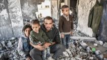 رجُل فلسطيني وأطفاله بين أنقاض بيتهم المدمّر في غزّة، 5 كانون الثاني/ يناير 2024 (Getty)