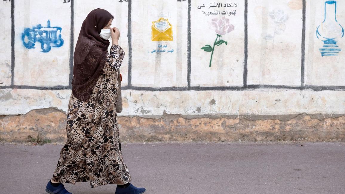 امرأة تمر عبر جدار رسمت عليه رموز بعض الأحزاب السياسية المتنافسة في الانتخابات المقبلة بالعاصمة المغربية الرباط ، في غشت 2021
