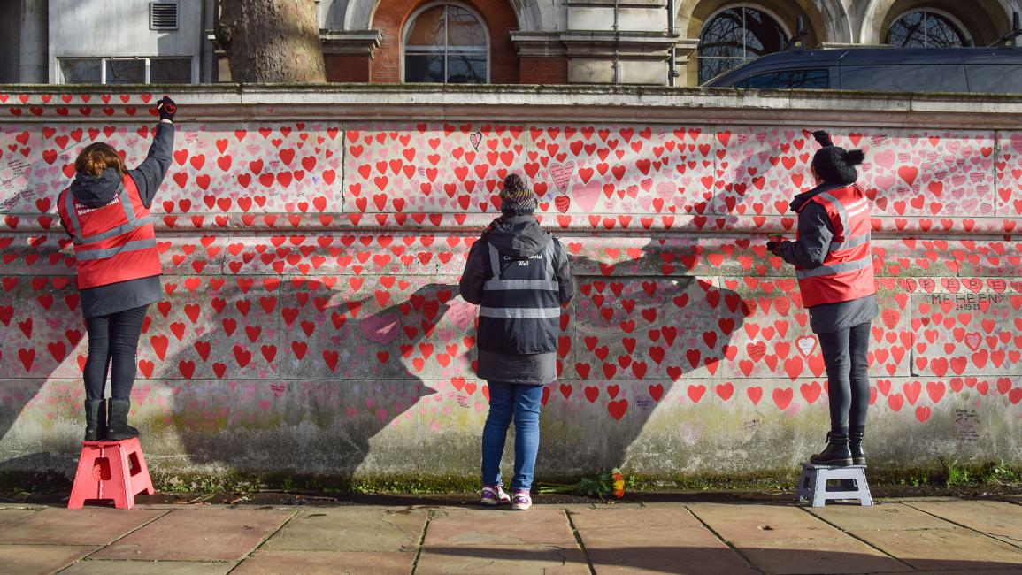 متطوعون يرسمون قلوباً حمراء على نصب كوفيد التذكاري (Vuk Valcic/ Getty)
