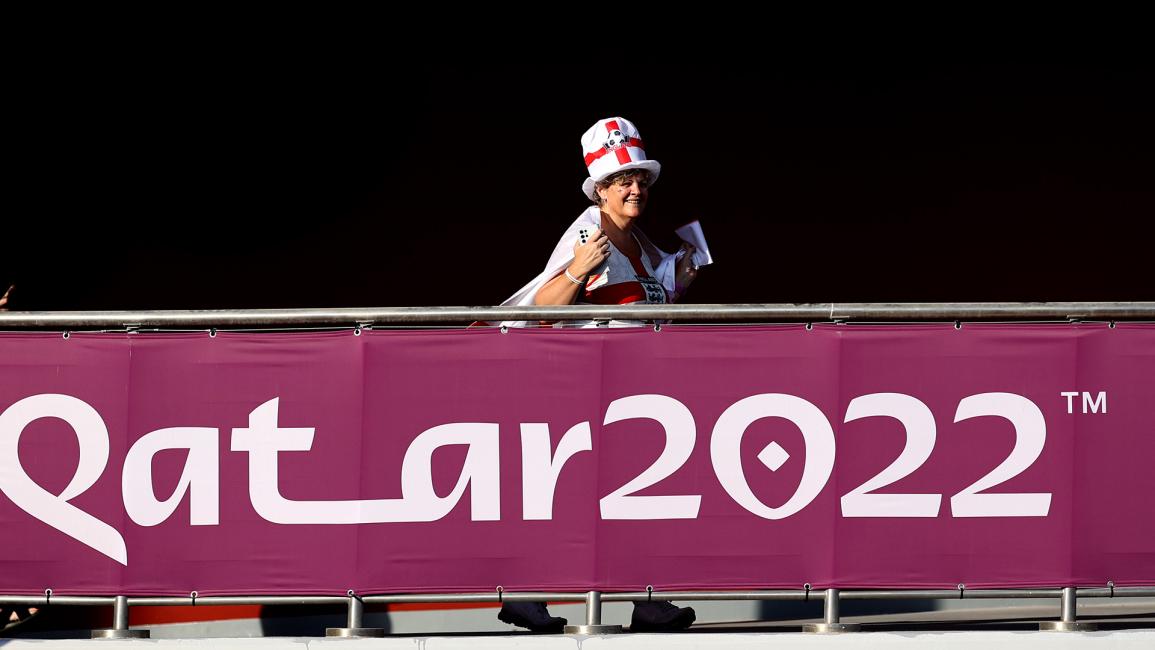 مشجعة منتخب إنكلترا ترتدي ملابس تنكرية، أمام لافتة تشير إلى قطر 2022 (شارلوت ويلسون / Getty)
