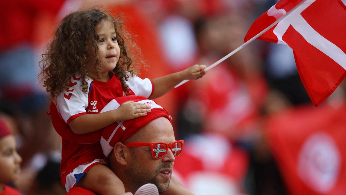 مشجع من الدنمارك يحمل ابنته داخل الملعب (كاي بفافنباخ/رويترز)