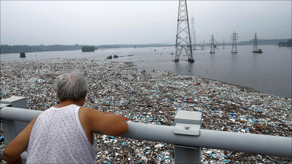 تتجمع القمامة على نهر غمرته الفيضانات (رويترز/تينغشو وانغ)
