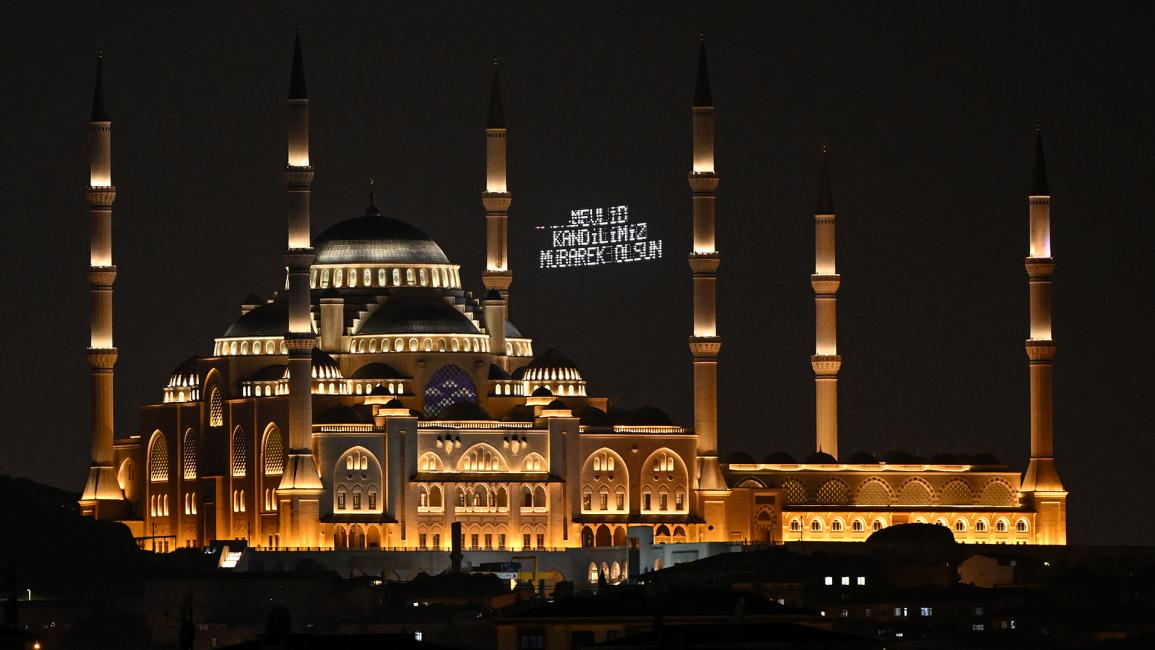 رسالة تهنئة مضيئة معلّقة بين مئذنتي مسجد تشامليجا الكبير في إسطنبول، تركيا (علي أتمجة/Getty)