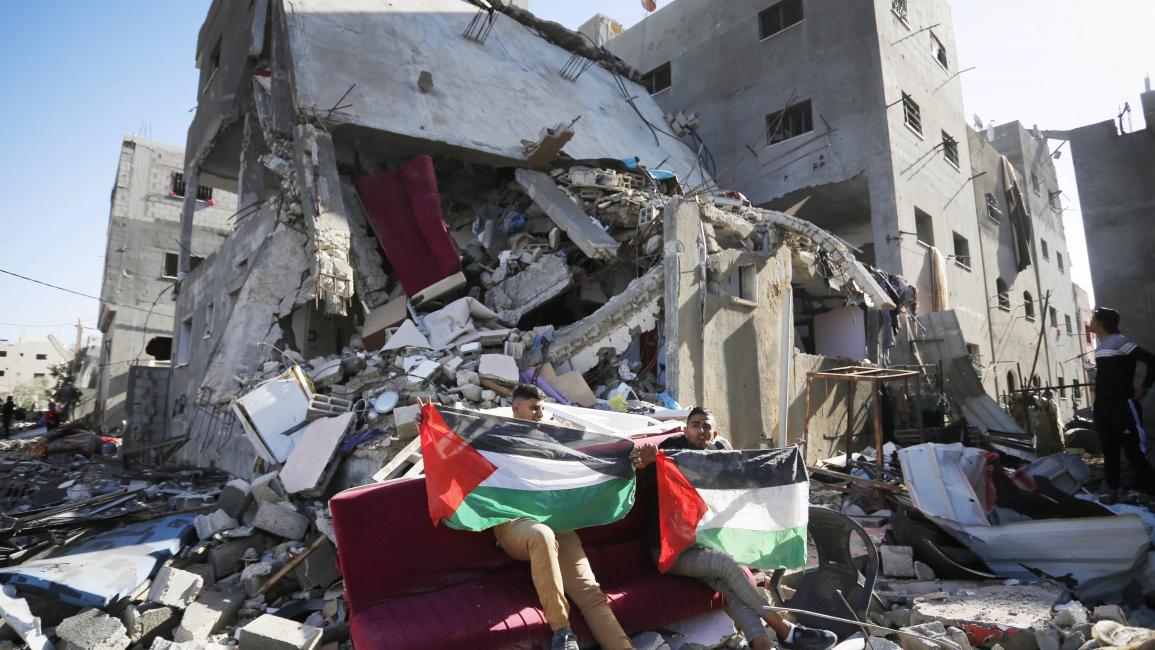 يرفعان علم فلسطين فوق الركام (أشرف أبو عمرة/الأناضول)