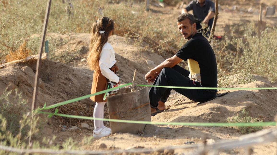 فلسطيني يصطحب ابنته لزيارة القبور في اليوم الأول من العيد (داود أبو الكاس/الأناضول)