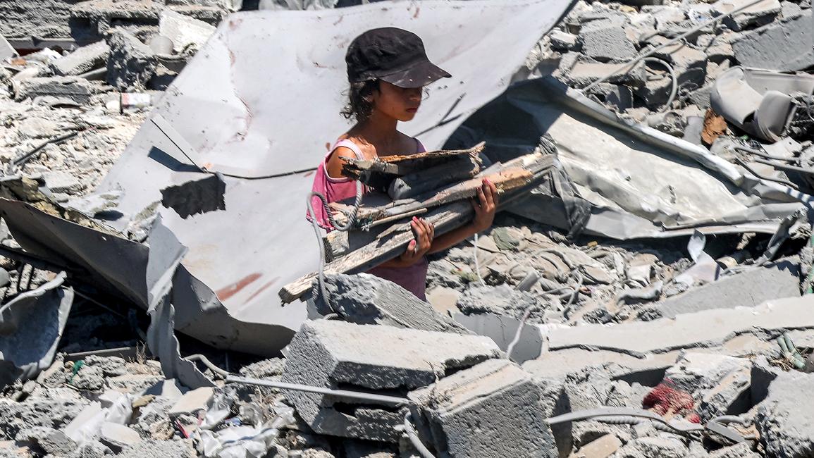 طفلة تجمع الخشب من وسط الأنقاض والدمار اللذين خلّفهما الاحتلال الاسرائيلي (عمر القطاع/ Getty)