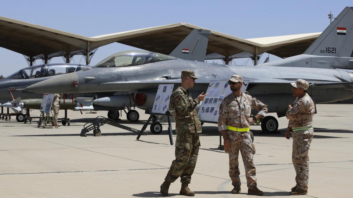جنود من التحالف الدولي قرب طائرة أف 16 أميركية في قاعدة الجوية شمال بغداد (24/4/2024 فرانس برس)