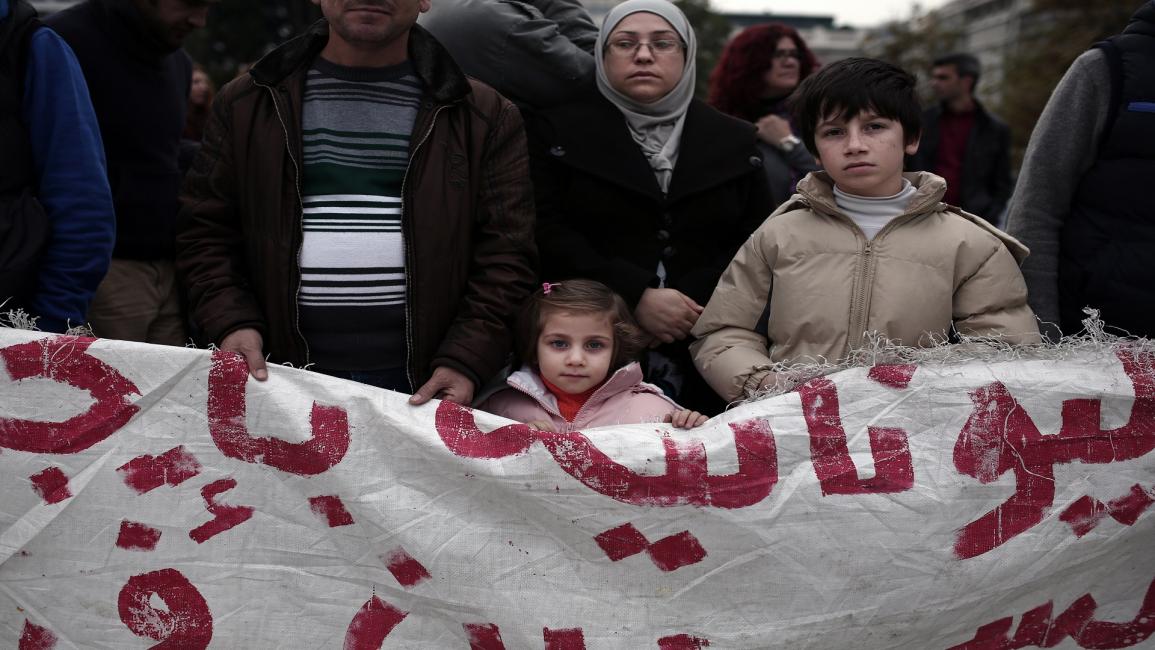 عائلة سورية لاجئة أمام مبنى برلمان اليونان (فرانس برس)