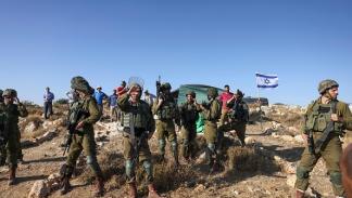 جنود للاحتلال يحرسون مستوطنين في قرية حلحول، الخليل 1 أغسطس 2023 (حازم بدر/فرانس برس)