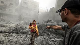 ناجية مع طفلتها من قصف إسرائيلي استهدف مدينة غزة، 23 أكتوبر 2023 (الأناضول)