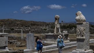 سائحتين تتجولان في الموقع الأثري لجزيرة ديلوس، 24 مايو 2024 (أريس ميسينيس فرانس برس)