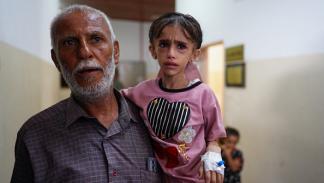طفلة فلسطينية مريضة رفقة والدها بمستشفى خانيونس، 24 يونيو(فرانس برس)
