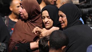 فلسطينيات يبكين شهداء قضوا في قصف إسرائيلي وسط قطاع غزة (Getty)