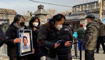 أقارب ضحايا كورونا يحملون صورا لأحبابهم قرب محرقة للجثث في بكين (Getty)