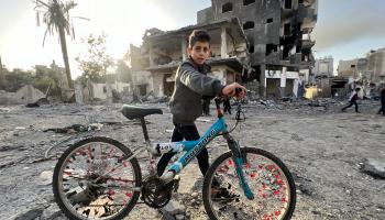 طفل فلسطيني يسير بدراجته وسط الدمار الذي خلفه القصف الصهيوني بمدينة غزة، 24 تشرين الثاني/ نوفمبر (Getty)