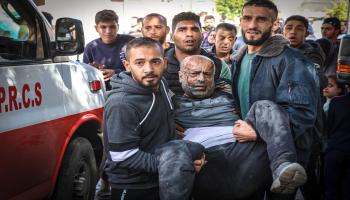  فلسطينيون يحملون رجلاً فلسطينياً إلى المشفى، أصيب بقصف إسرائيلي على مبنى سكني في خانيونس جنوبيّ قطاع غزّة في 8/ 12/ 2023 (فرانس برس)