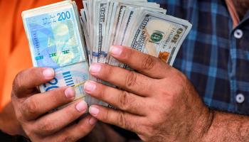 مواطن يصرف دولارات مقابل الشيكل في غزة / 2 يوليو 2024، (بشار طالب/ Getty)