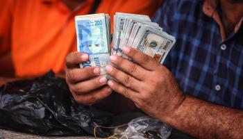 رجل يحسب الدولار بعد صرف شواقل بغزة،2 يوليو 2024،(مجدي فتحي/Getty)
