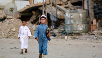 طفلان فلسطينيان يسيران للمشاركة بصلاة عيد الأضحى وسط الأنقاض في خانيونس جنوبي قطاع غزة 16/6/2024 (بشار طالب/فرانس برس)
