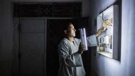 مصري يقوم بتوصيل مولد كهربائي لتشغيل منزله بعد انقطاع الكهرباء، 12 يونيو 2023(Getty)