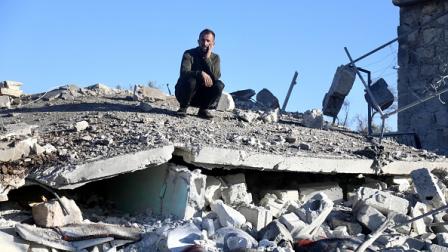 رجل يجلس على أنقاض منزل دُمّر جراء غارة في إدلب، 26 ديسمبر 2023 (عز الدين قاسم/الأناضول)