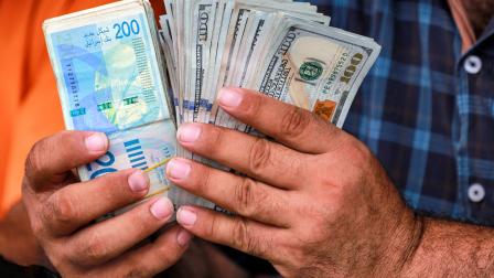 مواطن يصرف دولارات مقابل الشيكل في غزة / 2 يوليو 2024، (بشار طالب/ Getty)