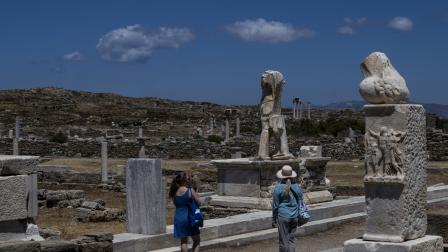 سائحتين تتجولان في الموقع الأثري لجزيرة ديلوس، 24 مايو 2024 (أريس ميسينيس فرانس برس)