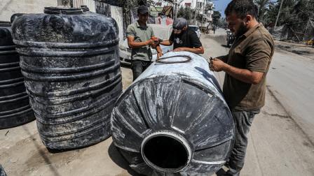 يصلحون خزانات المياه في دير البلح، 13 يونيو 2024 (الأناضول)