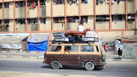 نازحون فلسطينيون يمرون بالقرب من مدرسة تستخدم كمأوى في دير البلح، 7 يوليو 2024 (فرانس برس)